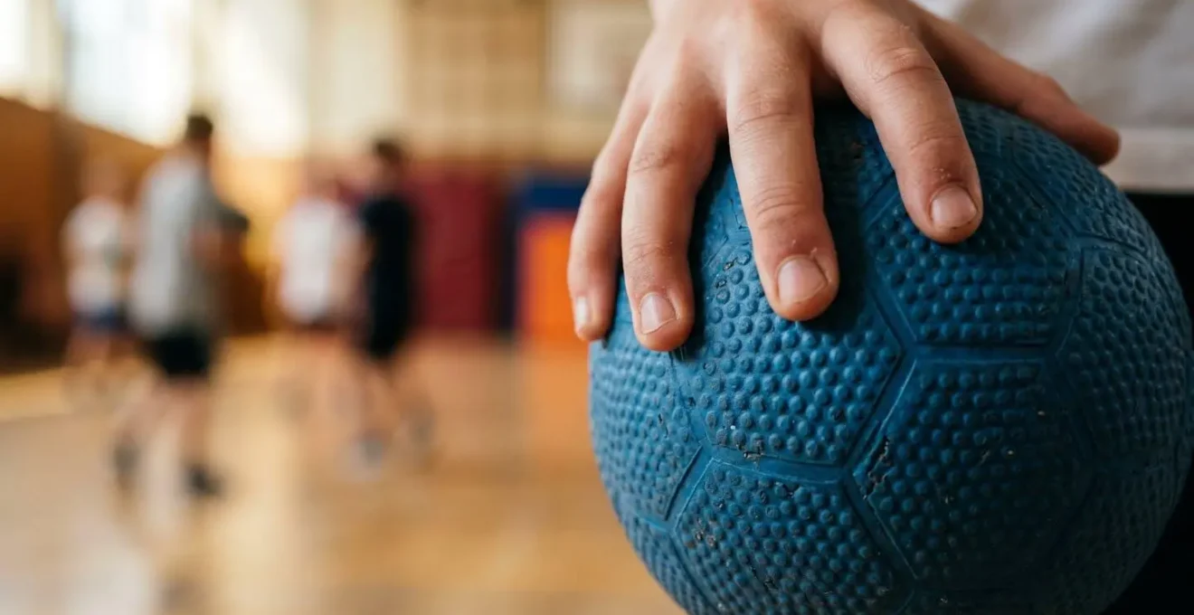 Gros plan sur un ballon de handball tenu dans la main d'un enfant prêt à faire une passe