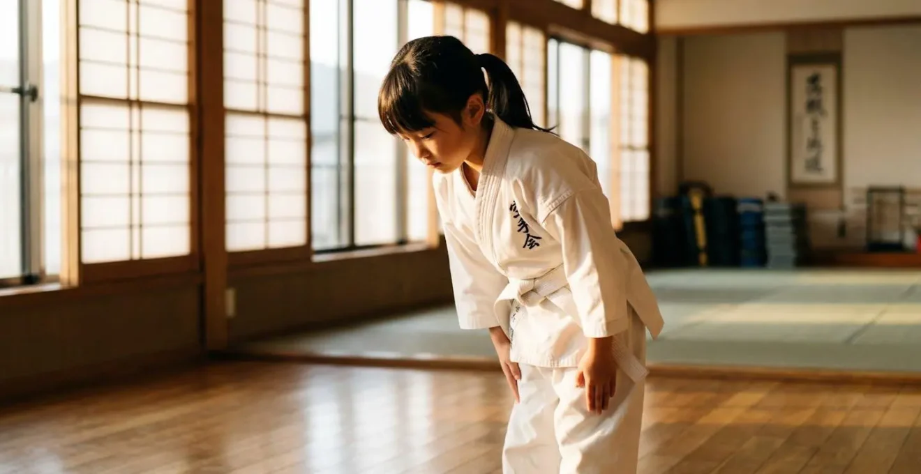 Enfant en kimono blanc effectuant le salut traditionnel dans un dojo de karaté