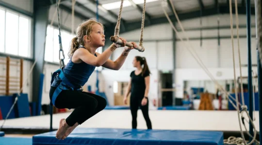 Enfant pratiquant le trapèze dans un cours de cirque, soutenu par un système de sécurité