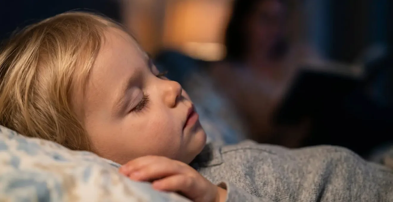 Gros plan sur le visage apaisé d'un enfant écoutant une histoire murmurée au coucher