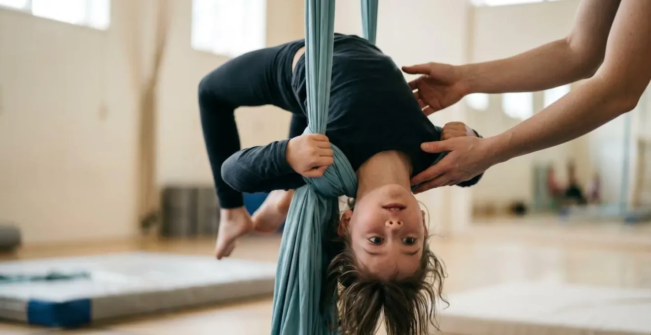 Vue en contre-plongée d'un enfant en position d'inversion sur un agrès aérien